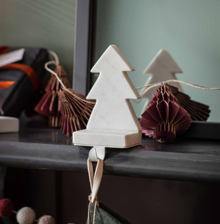 White marble Christmas tree stocking holder on a mantel with decorations.