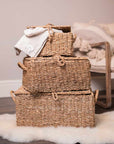 3 woven seagrass storage trunks piled up on furry rug.