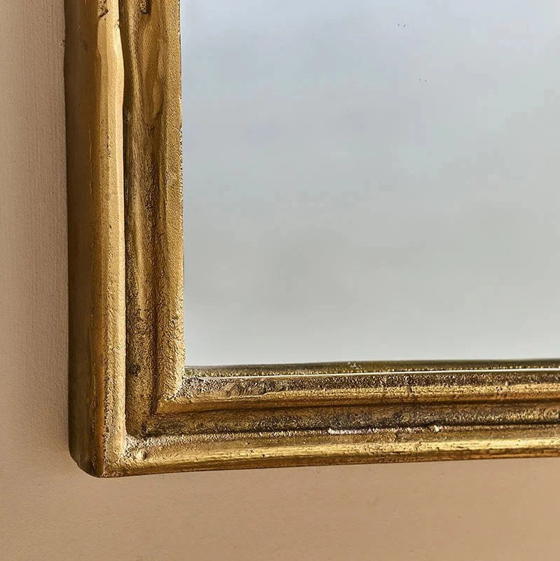 Close up of antiqued brass arched mirror.