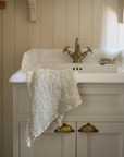 Neutral waffle hand towel draped over a sink.