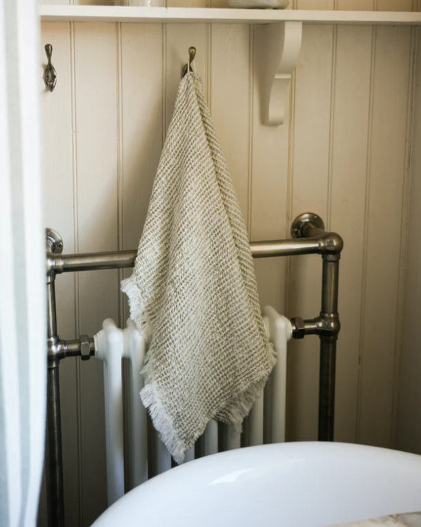 Neutral waffle hand towel on a brass hook in bathroom.