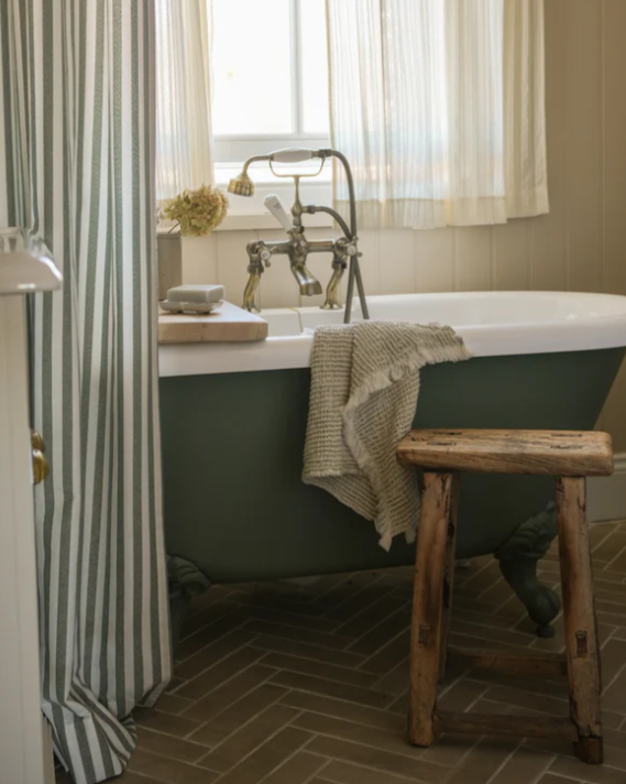 Neutral waffle hand towel draped over green standalone bath.