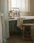 Neutral waffle hand towel draped over green standalone bath.