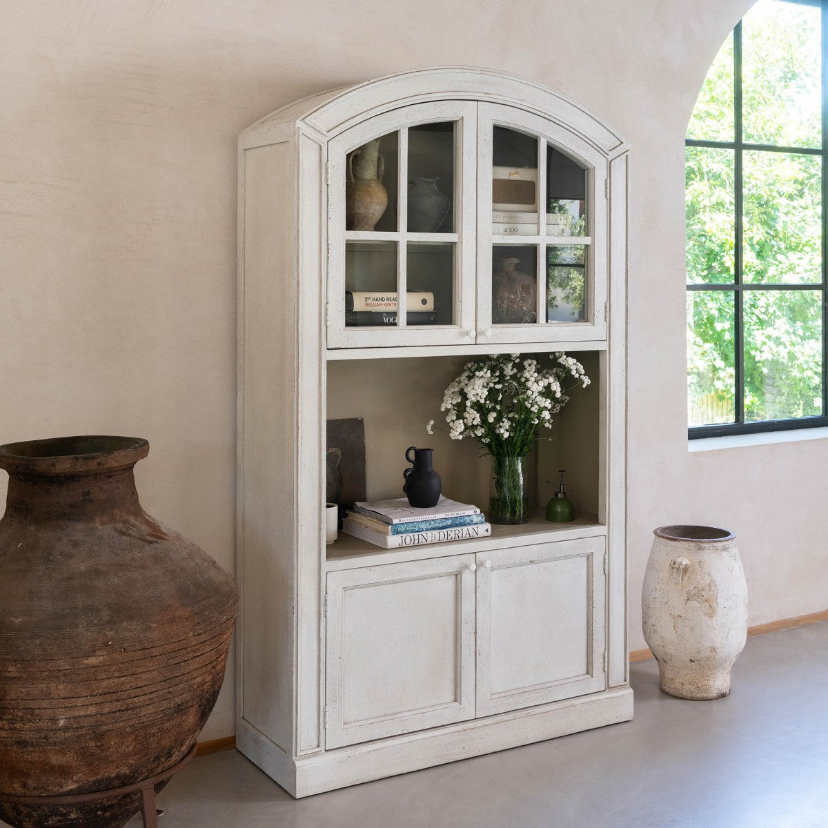 arched cabinet with flowers and rustic pots in bright room.