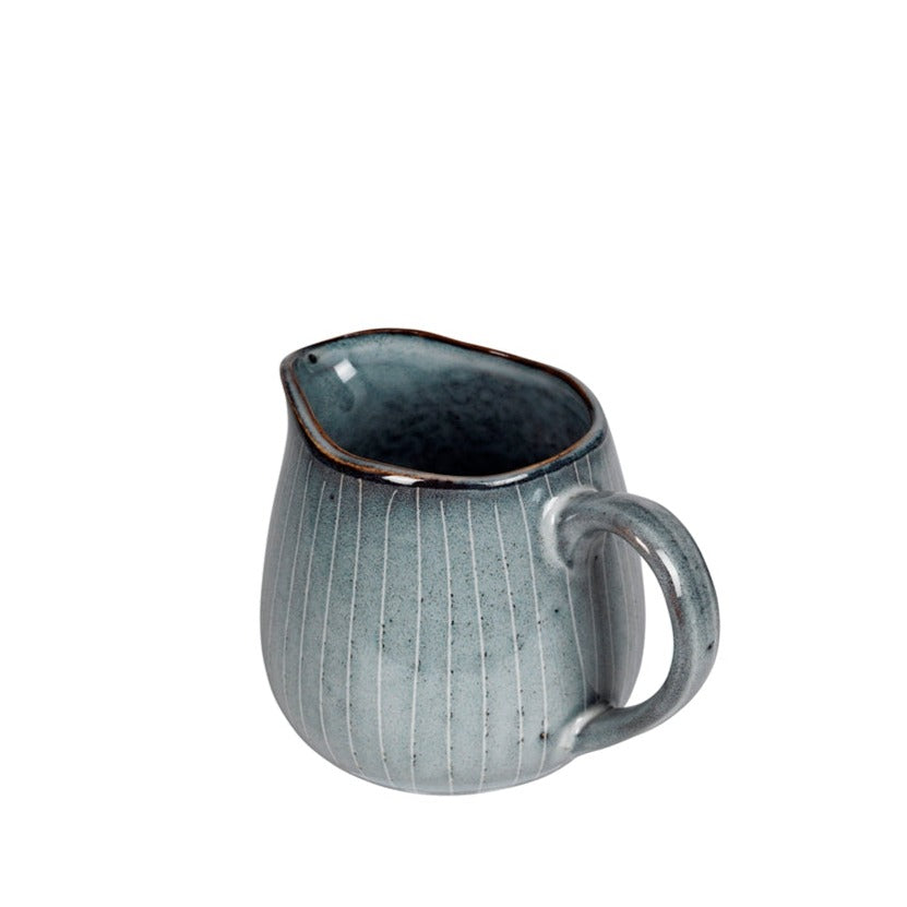 View of handle and mouth of blue glazed milk jug.
