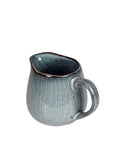 View of handle and mouth of blue glazed milk jug.