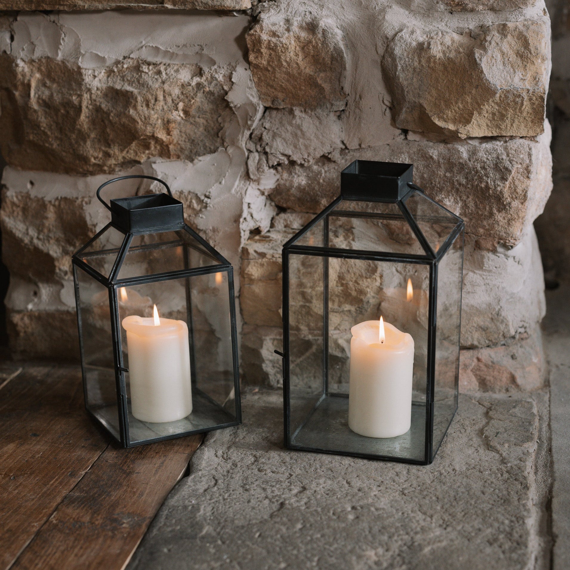 Set of two black and Glass Lanterns on stone hearth.