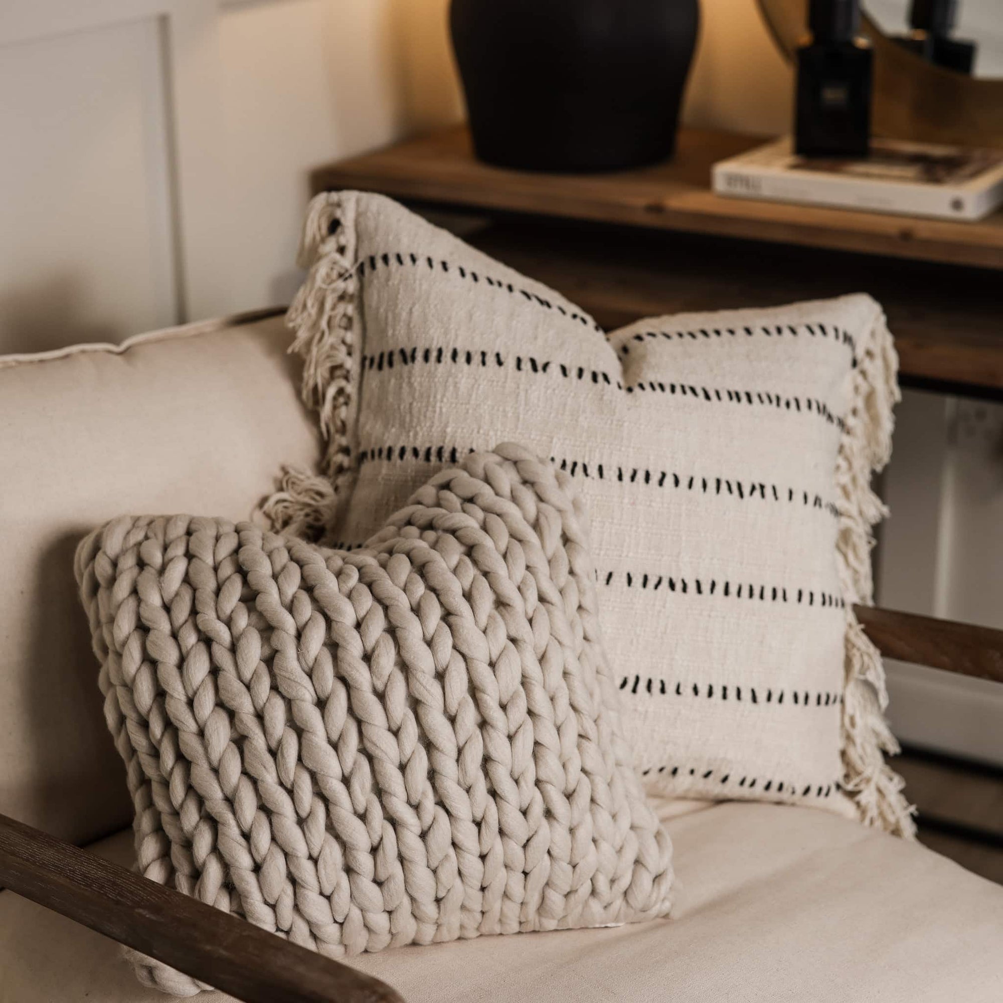 Knitted cushion and cream patterned cushion on an armchair