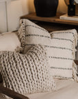 Knitted cushion and cream patterned cushion on an armchair