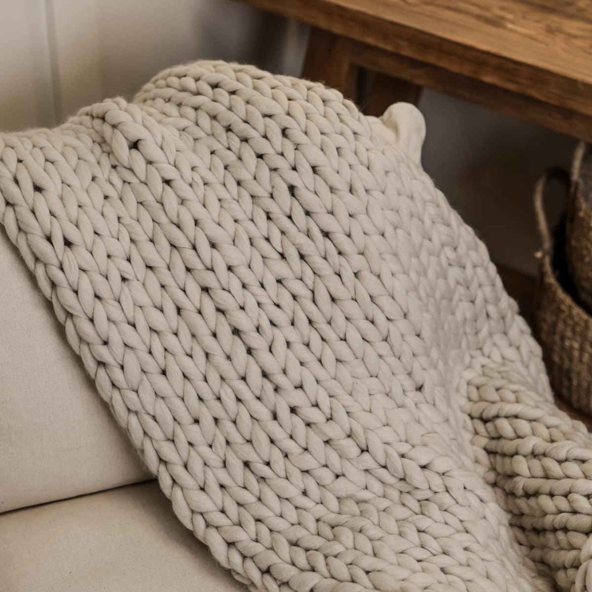 Chunky knitted blanket thrown over an armchair.