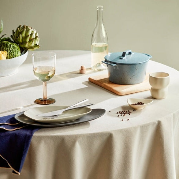 Natural oak chopping board on table with dinnerware.