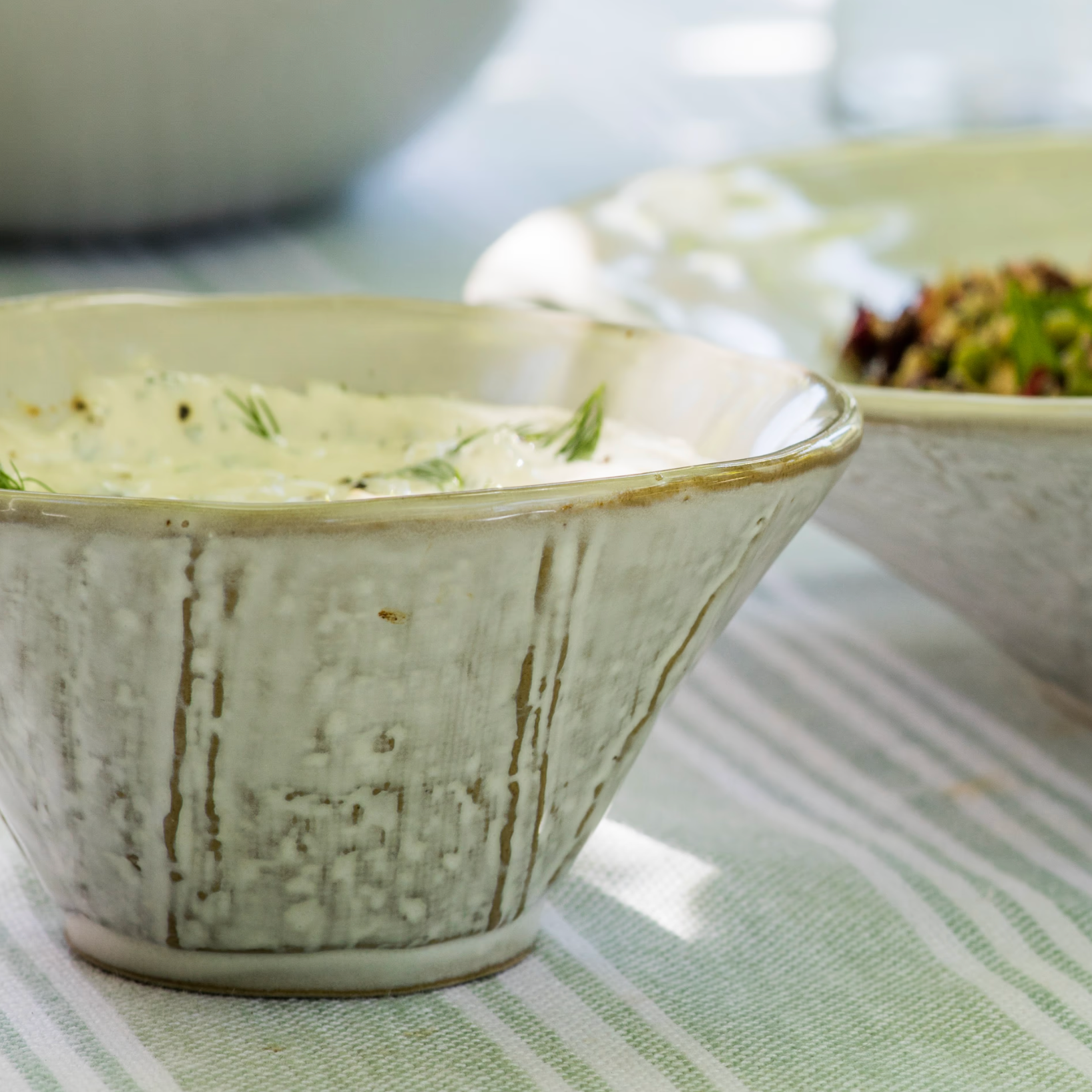 Rustic ceramic serving bowl on green table cloth. 