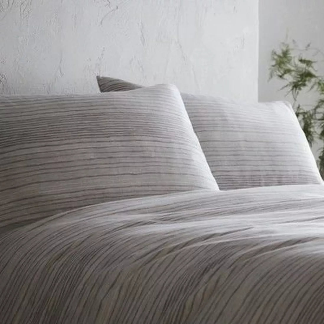 Grey striped bedding set on double bed with two pillows.