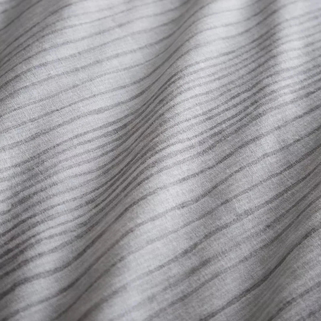 Close up of waved pattern on striped grey bedding set.