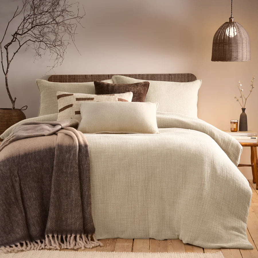 Natural cream bedding set in neutral bedroom with brown throws and cushions.