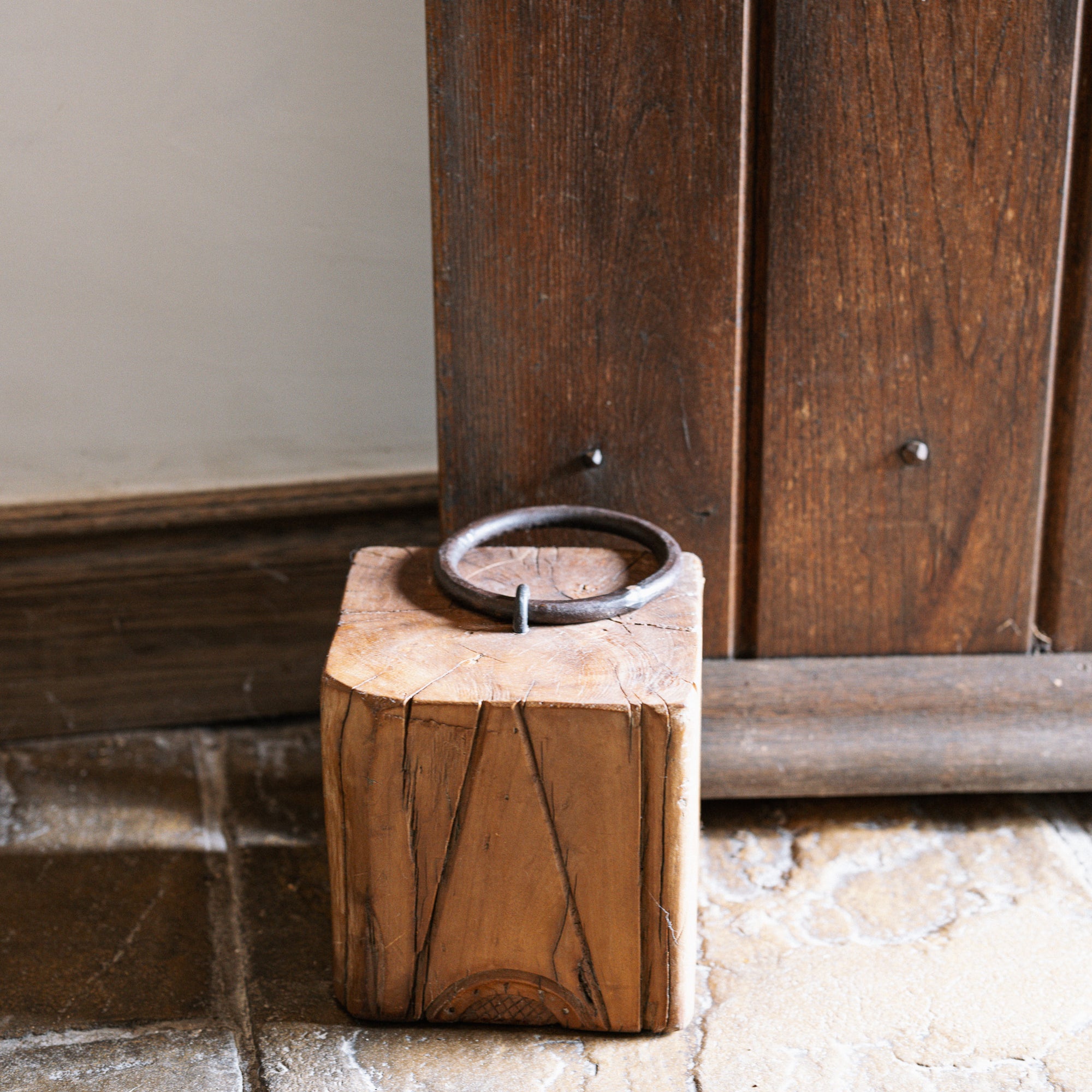 Reclaimed wooden doorstop with handle against a wooden door.