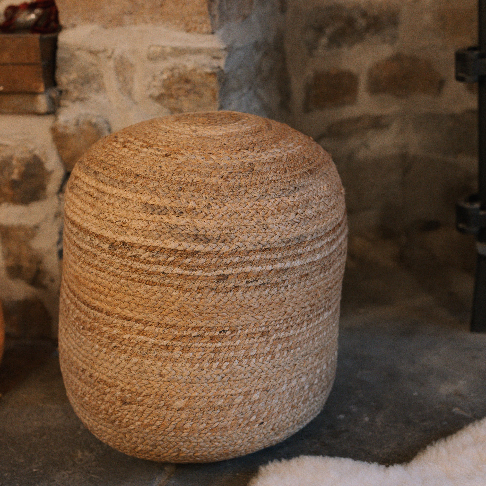 Round jute pouf by stone fire.