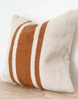 Rust and cream striped cushion on wooden surface.