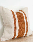 Rust and cream striped cushion on wooden surface.