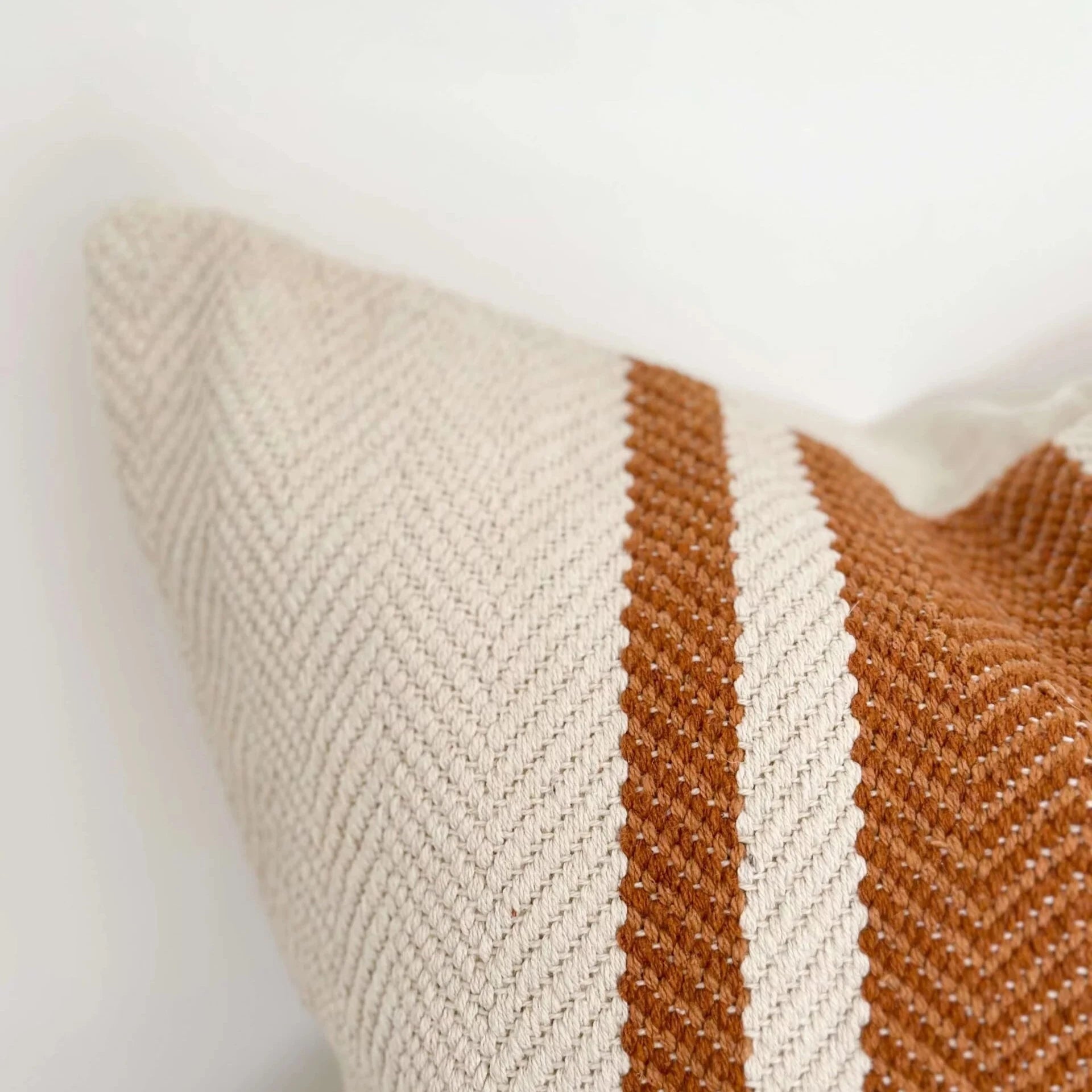 Close up of rust and cream striped cushion.