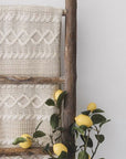 Wooden ladder with cream blanket over and faux lemon stems.