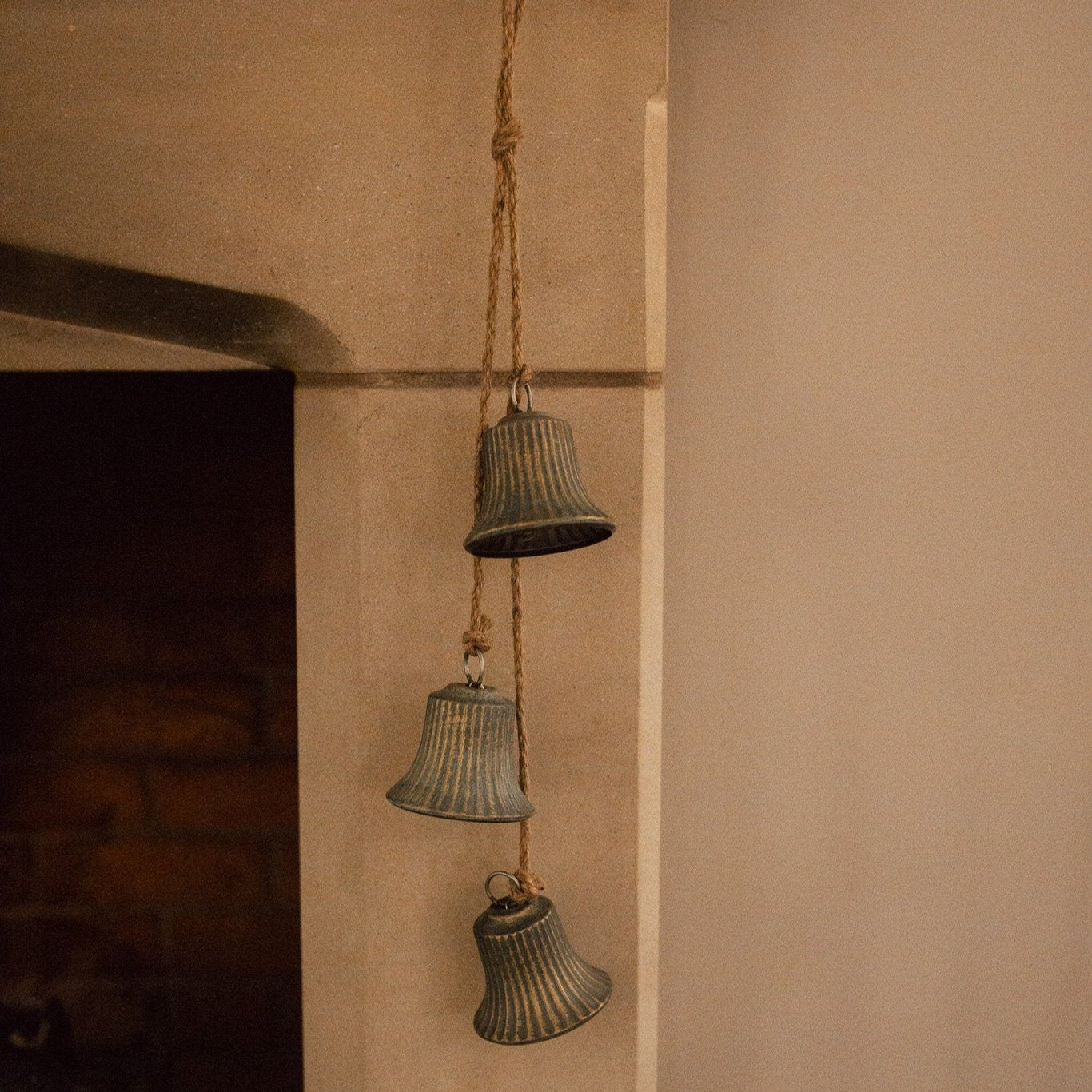 Rustic 3 bell garland, hanging from a mantelpiece with jute rope.