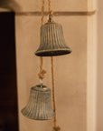 Close up rustic aged brass 3 bell garland hanging from a mantlepiece.