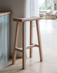 Natural oak wooden saddle stool at breakfast bar.