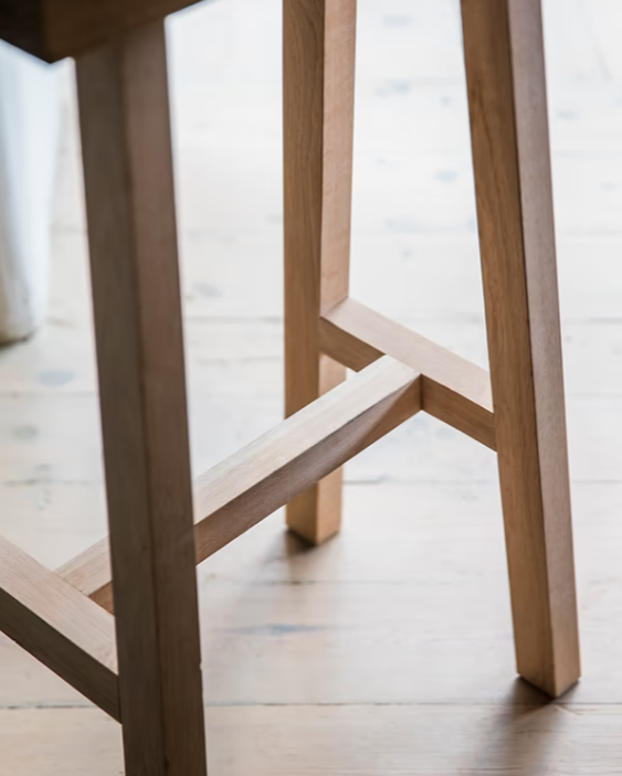 Close up of legs on natural wooden saddle stool.