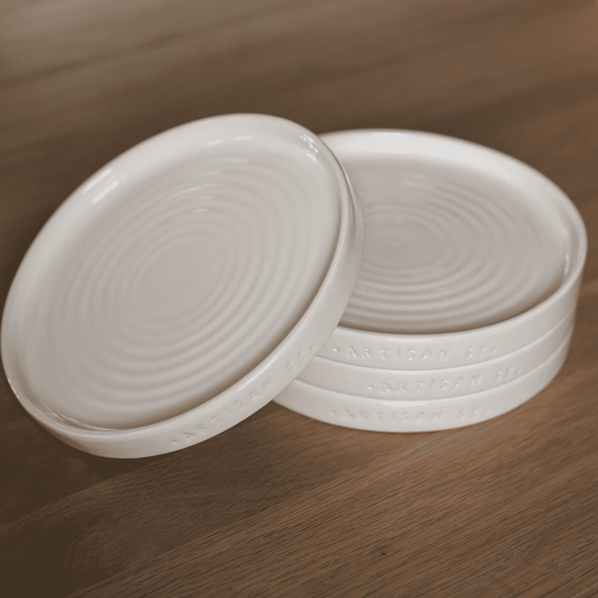 Set of four cream side plates on wooden table