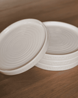 Set of four cream side plates on wooden table