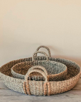 The Evelyn Seagrass Baskets stacked on a rustic wooden table. 