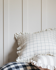 White Grid Ruffle Cushion sitting on a pile of other ruffle cushions.