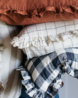 A cluster of striped, gingham and orange ruffle cushions.