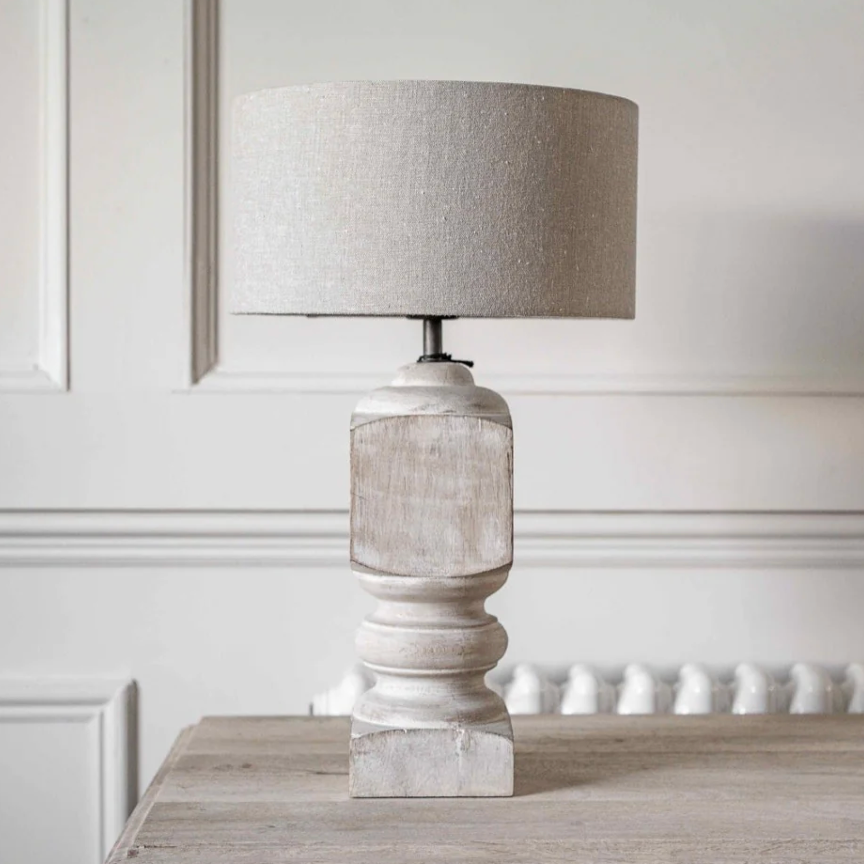 a turned Mango Wood Table Lamp with white washed effect on a wooden table.