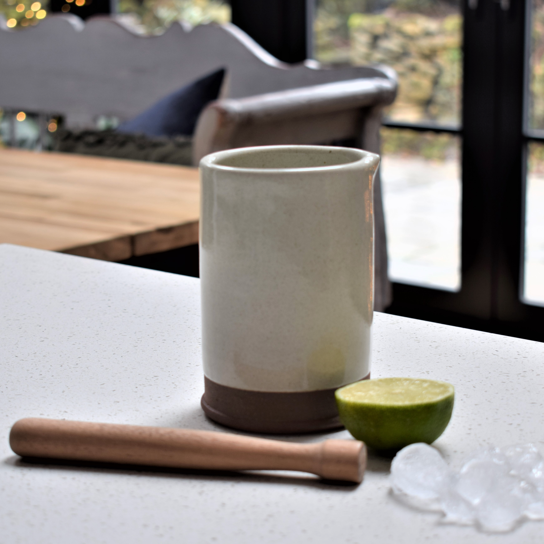A white stoneware cocktail gift set with a lime and some ice.