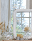 Two distressed white mirrors leaning against a wall with dried flowers.