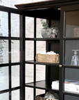 black armoire with decor items on shelves.