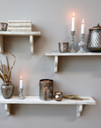 Set of three rustic white shelves with candles and decor.