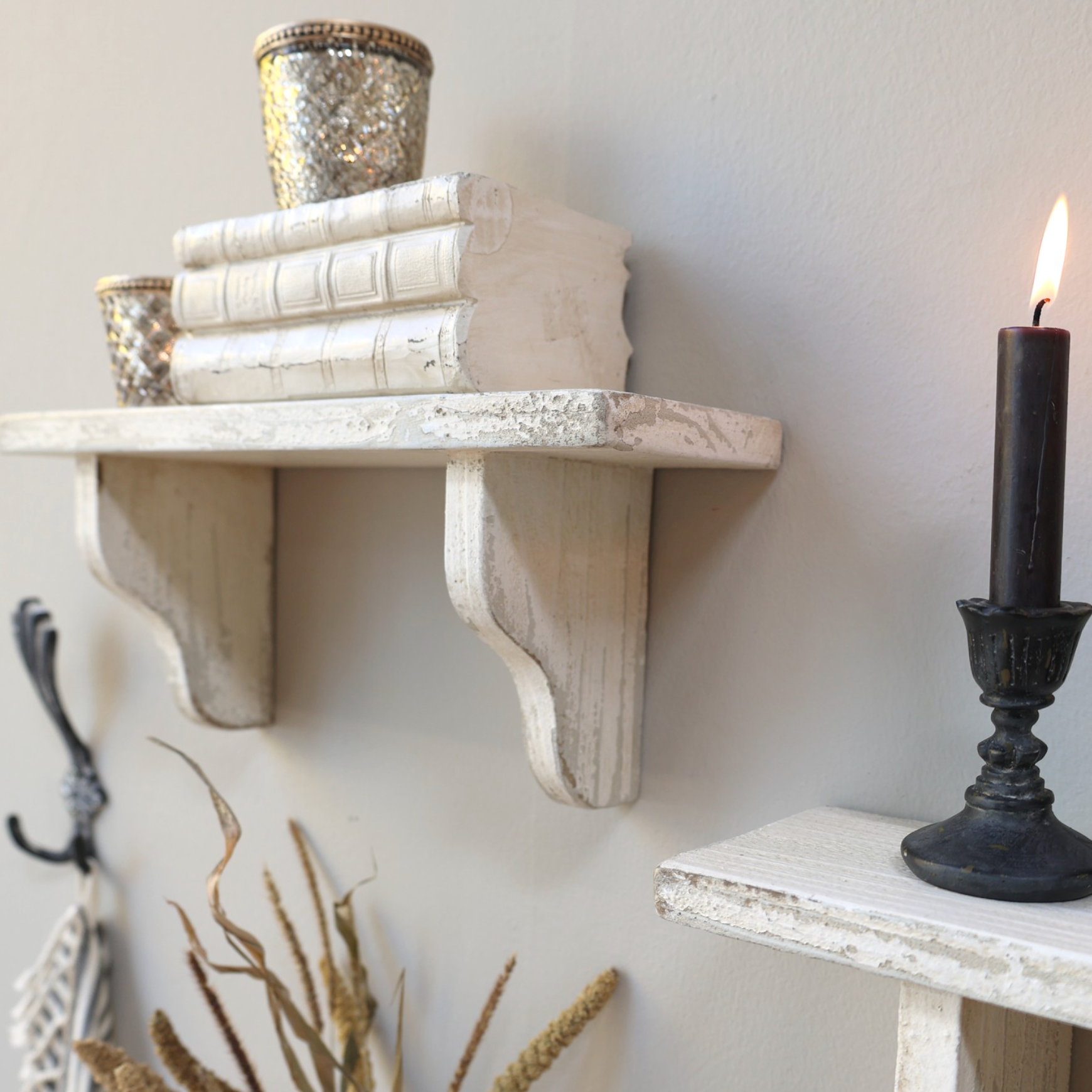 A rustic shelf with aged white finish and decor items.