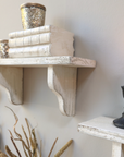 A rustic shelf with aged white finish and decor items.