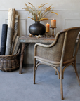 a rattan dining chair with a rustic console table and candles.