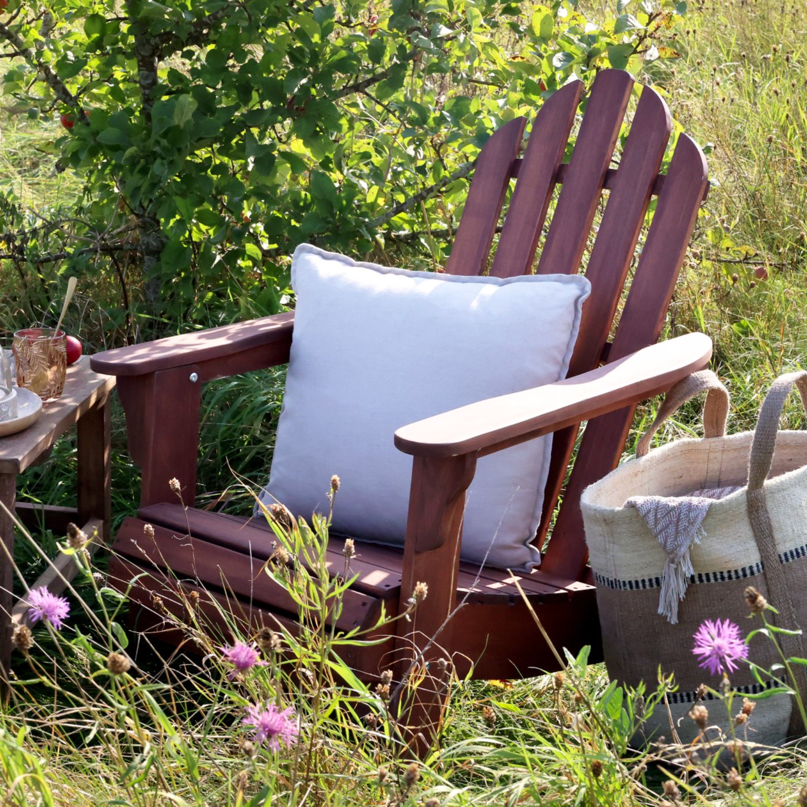 wooden armchair in garden with white cushion and basket.