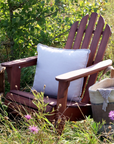 wooden armchair in garden with white cushion and basket.