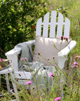 white wooden outdoor chair in field with wild flowers.