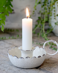 Candle Stick Holder with antique white finish and lit dinner candle. 