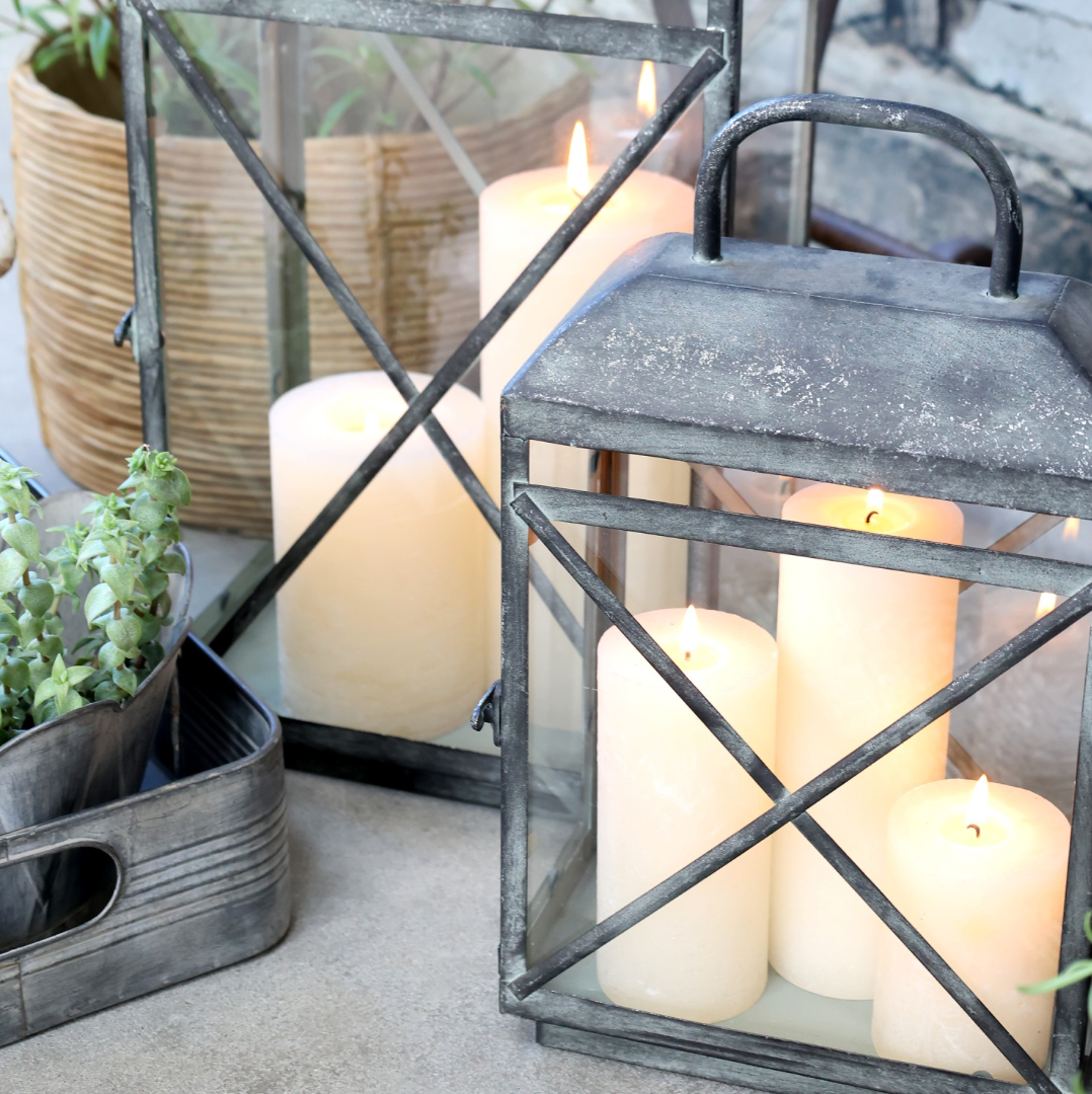 a close up shot of an antique zinc and glass lantern with lit candles.