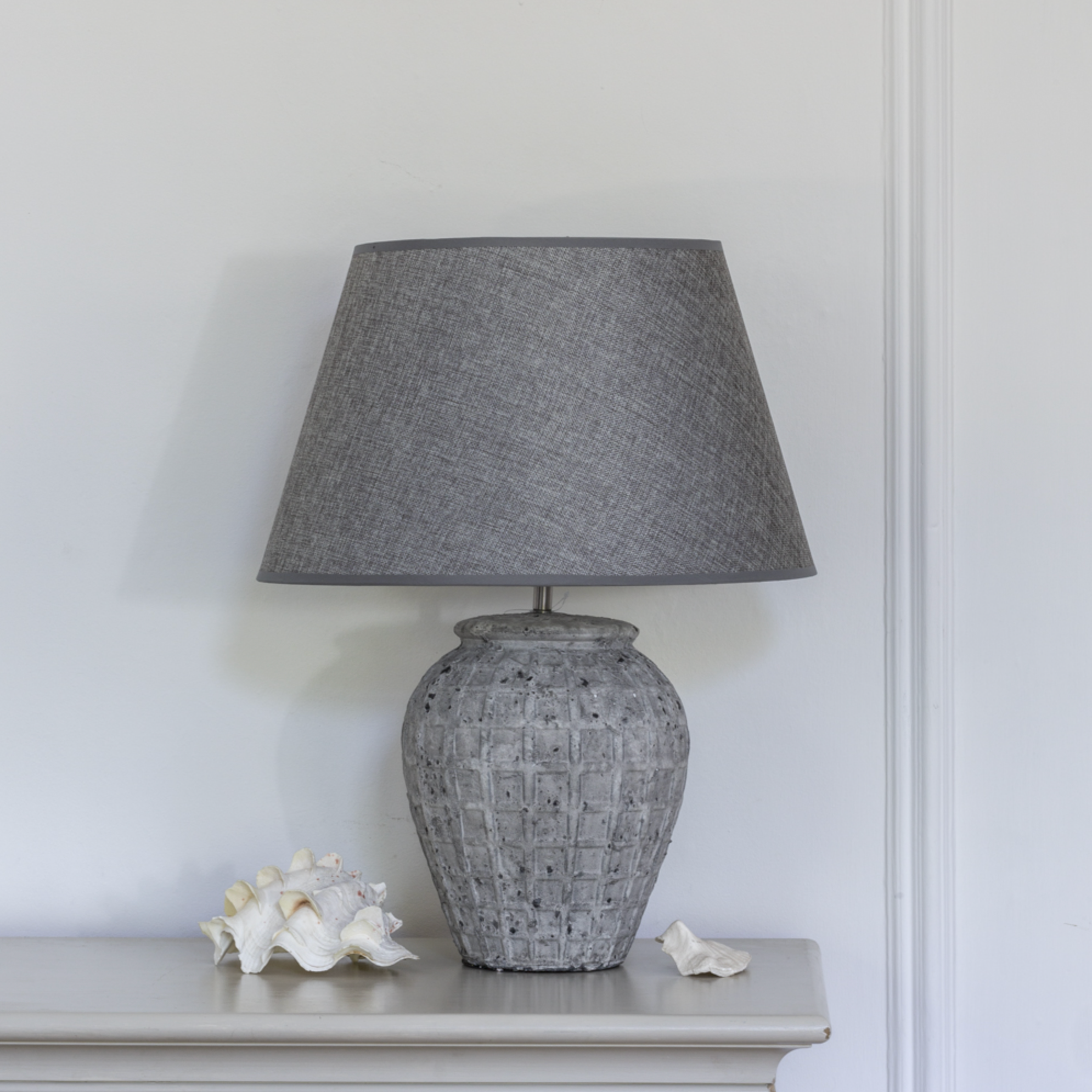 Grey Geometric Ceramic Lamp with Shade against panelled wall.