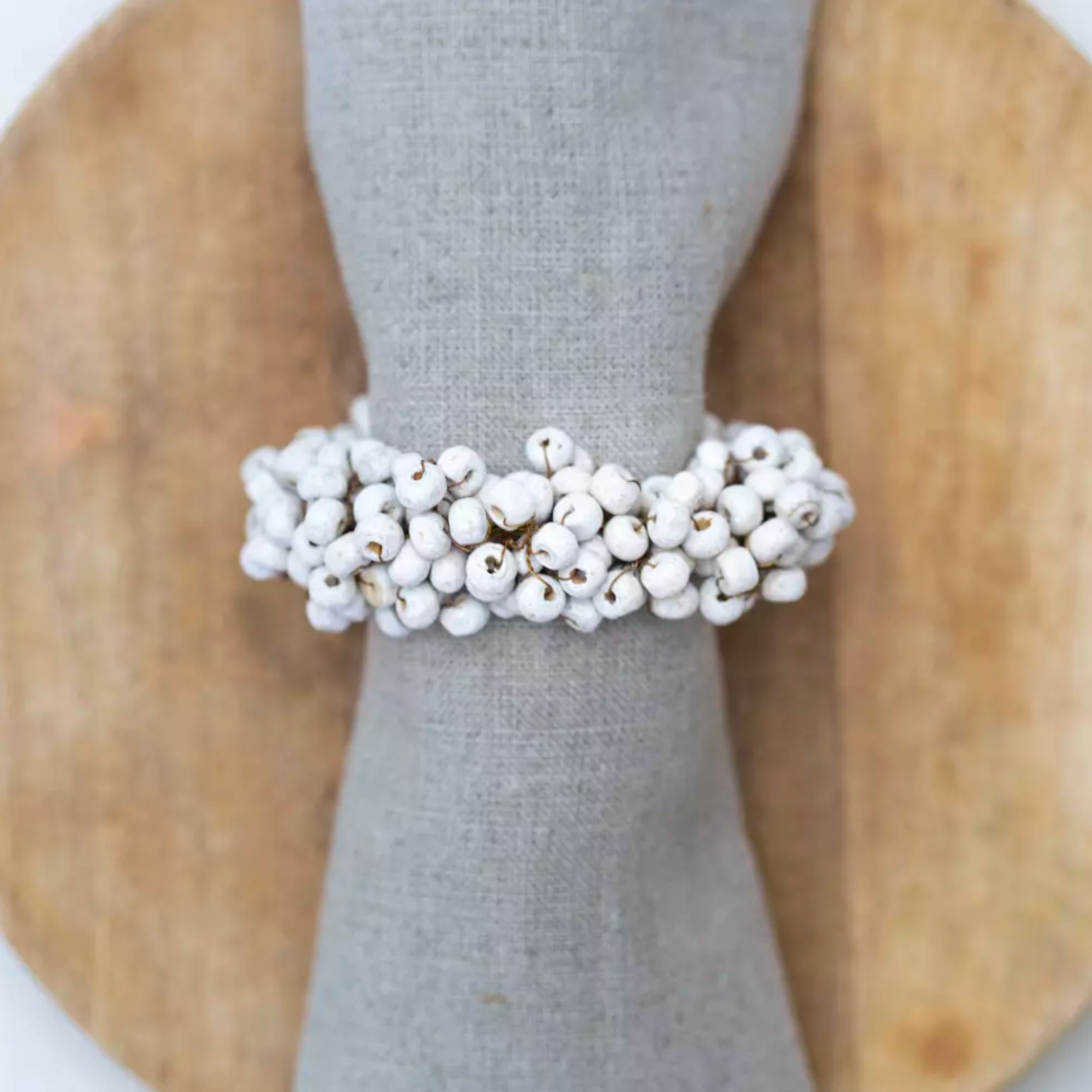 Wooden Napkin Ring with White Berries on a wooden plate.