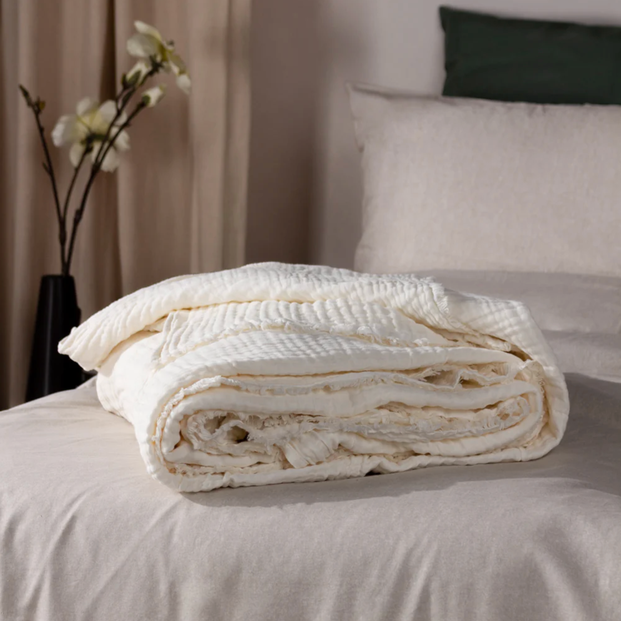 White Muslin Bedspread neatly folded on the end of a bed.